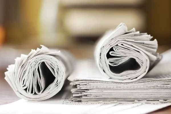 Newspapers. Rolled journal with news and pages with headlines and articles, side view, selective focus