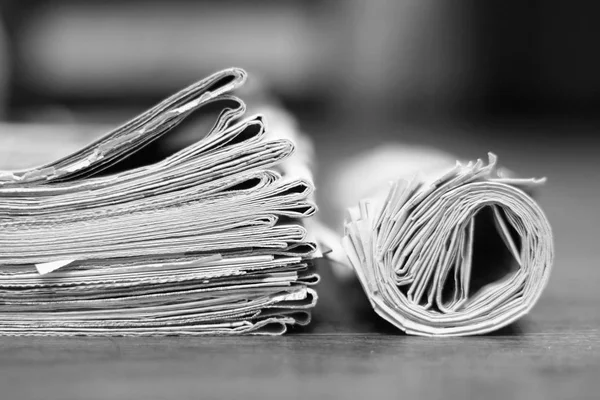 Newspapers in office. Rolled and folded papers with news on wooden table. Tabloid journals stacked in pile, side view