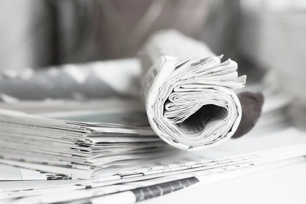 Folded newspapers stacked in pile and pages with headlines and articles, top view