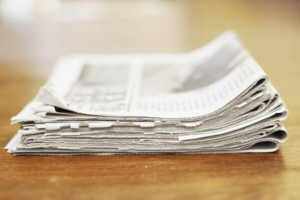 Куча свежих утренних газет на столе в офисе. Последние финансовые и деловые новости в ежедневной газете. Страницы с информацией (заголовки, статьи, фотографии, текст). Складные и сложенные журналы
 