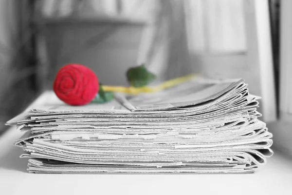 Gazeteler ve gül yığını. Yığın ve kırmızı çiçek, yan görünüm haber ile birçok kağıtları yığılmış