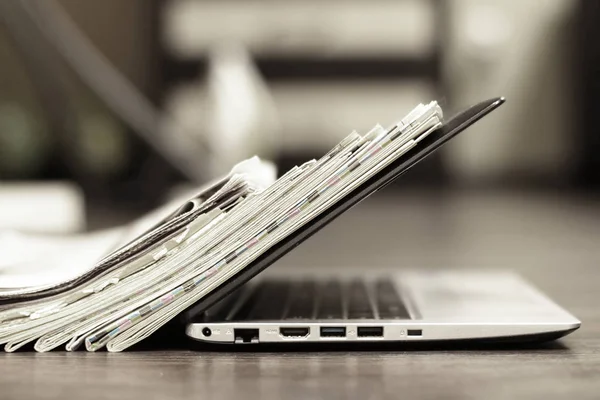Açık laptop ve Gazeteler yığını. Günlük günlüklerin haber ve kişisel bilgisayar ile. Kavramı için farklı bilgi kaynakları - dijital cihaz ekran veya kağıt sayfaları