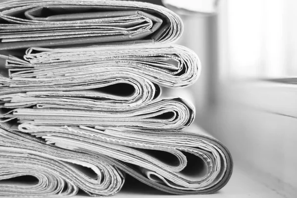 News - Folded newspapers stacked in row, selective focus on papers with blurred background. Paper texture