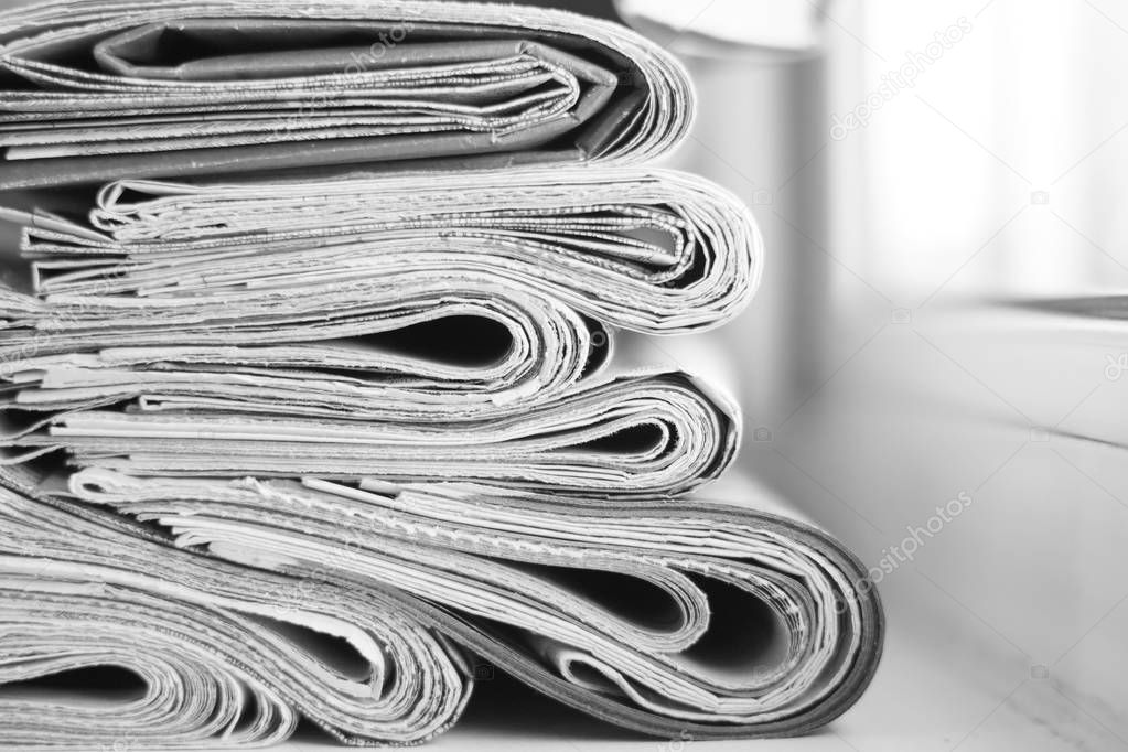 News - Folded newspapers stacked in row, selective focus on papers with blurred background. Paper texture 