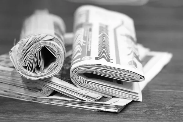 Katlanmış ve yığın ahşap masa üzerinde yığılmış Gazeteler haddelenmiş, yan görüntülemek  