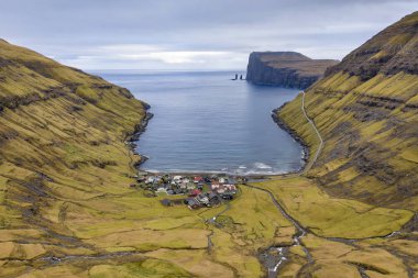 Aerial view over the village of Tjornuvik with the sea stacks Risin and Kellingin (the giant and the wtich) in the distance off the northern coast of  the island of Eysturoy in the Faroe Islands. clipart