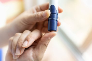 Lancet kan su kontrol etmek için parmağına kullanarak kadın elinde yakın çekim