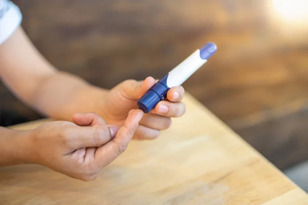 Primer plano de las manos de la mujer usando lanceta en el dedo para comprobar su sangre — Foto de Stock