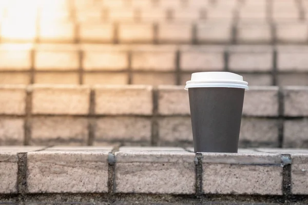 Close up of take away paper cup of hot coffee on stone tile stai