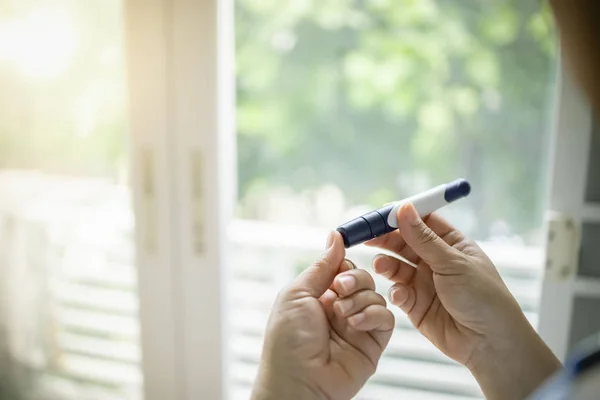 Close up of woman hands using lancet on finger to check blood su — Stock Photo, Image