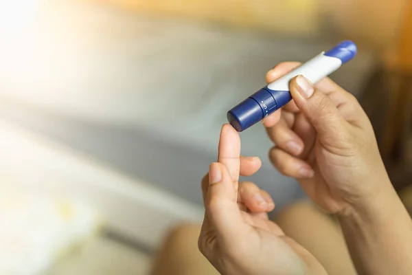 Primo piano delle mani della donna con lancetta sul dito per controllare il sangue su — Foto Stock