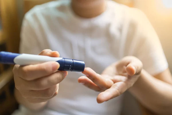 Lancet kan su kontrol etmek için parmağına kullanarak kadın elinde yakın çekim