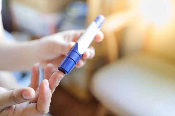 Close up of woman hands using lancet on finger to check blood su — Stock Photo, Image