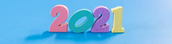 2021 New Year, Cover page Concept. Close up of colorful wooden number on blue background with light and shadow.