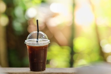 Yakın plan plastik kahve fincanı ahşap masa üzerinde fotokopi alanı olan Americano..