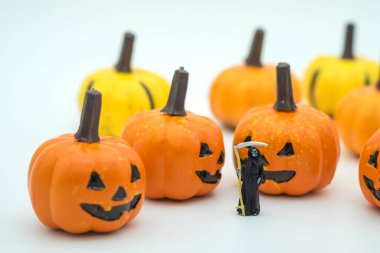 Ölüm Şeytanı minyatür figürünün yaklaşması Cadılar Bayramı balkabağı yüzlü beyaz arka planda Jack.