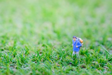 Seyahat ve sırt çantası konsepti. Gezgin minyatür figürler Sırt çantalı insanlar Freen çimenlerde yürüyorlar