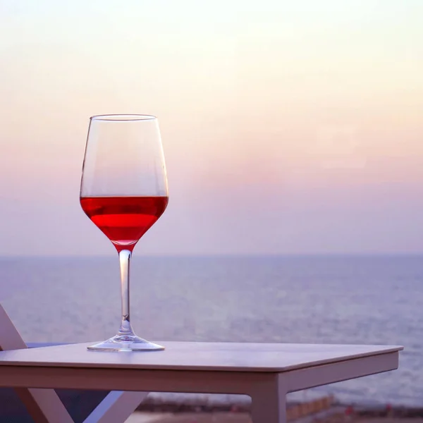 Bicchiere Vino Rosso Piedi Tavolo Uno Sfondo Orizzonte Marino Tramonto — Foto Stock