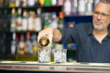 Barmen adam viski otel barının istemciye dökülen. Hizmet kavramı. Cam üzerinde odaklanmak.