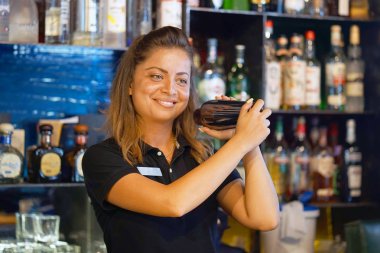 Bir shaker taze ve lezzetli bir kokteyl ile elinde tutan profesyonel Barmen kız. Barmen gibi o barın arkasında duran bir kokteyl shaker sallayarak bir müşteri için bir içki karıştırma.