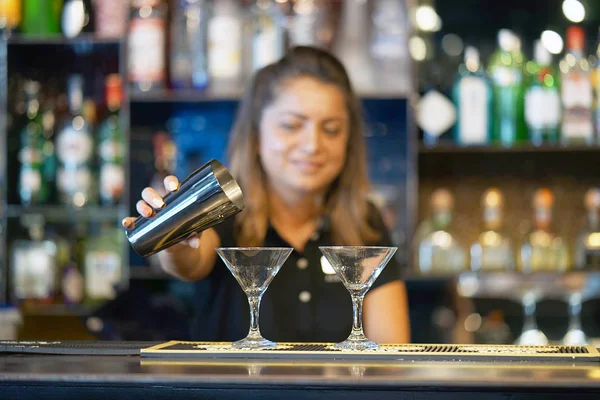 Professional barman girl pours a fresh cocktail to the customers of the hotel bar. The concept of service. Focus on the glass.
