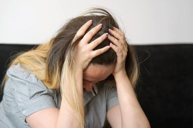 Baş ağrısı migren ağrısı evde kanepe üzerinde acı bir kadın. Sağlık sorunu, stres ve depresyon. Erkek el ile kafa tutar. Sağlık kavramı.