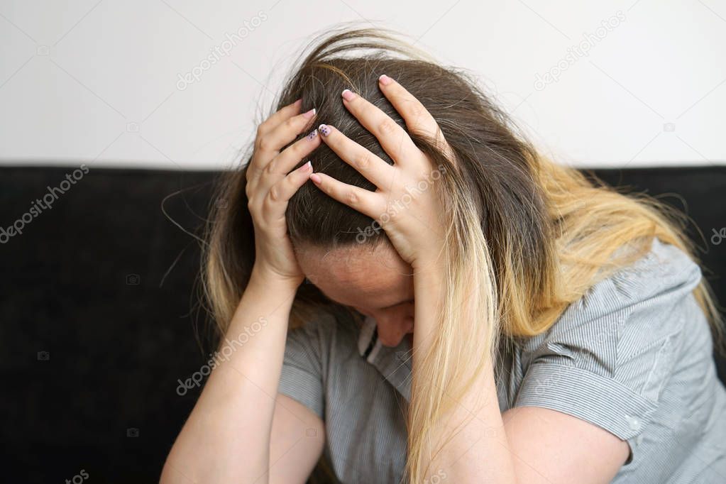 Loss of a loved one. Grief in the family. Death of a child. Sad depressed woman at home, sitting on the couch. Very sad young woman. concept of loneliness and pain