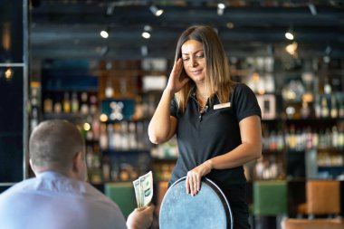 Garson kız otelin barında istemciden bir ipucu almak reddediyor. Sinirli bir kızdır. Kız üzgün ve istemcinin edepsizlik tarafından çileden. Duygular. Hizmet kavramı.