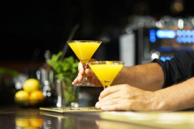 Barmen bir kokteyl otel barının istemciye verir. Taze kokteyl ile portakal. Alkollü, alkolsüz içki-içecek barda gece kulübüne karşı. Turuncu kokteyl bardak.