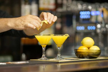Barmen kokteyl limon kabuğu ile dekorasyon. Taze kokteyl ile portakal. Alkollü, alkolsüz içki-içecek barda gece kulübüne karşı. Turuncu kokteyl bardak.