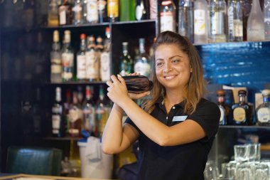 Bir shaker taze ve lezzetli bir kokteyl ile elinde tutan profesyonel Barmen kız. Barmen gibi o barın arkasında duran bir kokteyl shaker sallayarak bir müşteri için bir içki karıştırma.