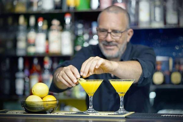 Barmen kokteyl limon kabuğu ile dekorasyon. Taze kokteyl ile portakal. Alkollü, alkolsüz içki-içecek barda gece kulübüne karşı. Turuncu kokteyl bardak.