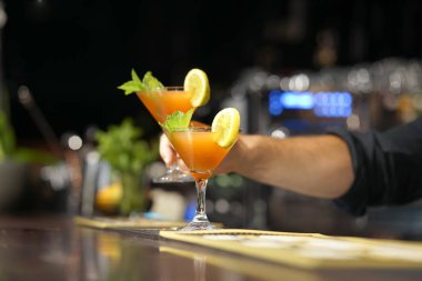 Barmen bir kokteyl otel barının istemciye verir. Taze kokteyl ile portakal. Alkollü, alkolsüz içki-içecek barda gece kulübüne karşı. Limon kokteyl bardak.