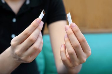Genç kadın bir sigara yırtılma. Kırık bir sigara onun elinde tutan kız. Sağlıklı bir yaşam tarzı kavramı. Sigarayı.