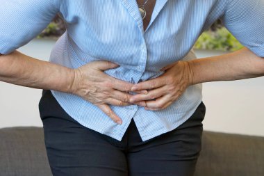 Yakın çekim görünümünü evde acı karın ağrısı olan bir yaşlı kadın. Kronik gastrit. Beden ve sağlık kavramı.