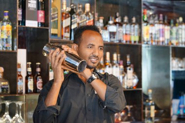 Bir shaker taze ve lezzetli bir kokteyl ile elinde tutan profesyonel barmen adam. Barmen gibi o barın arkasında duran bir kokteyl shaker sallayarak bir müşteri için bir içki karıştırma. Yakın çekim.