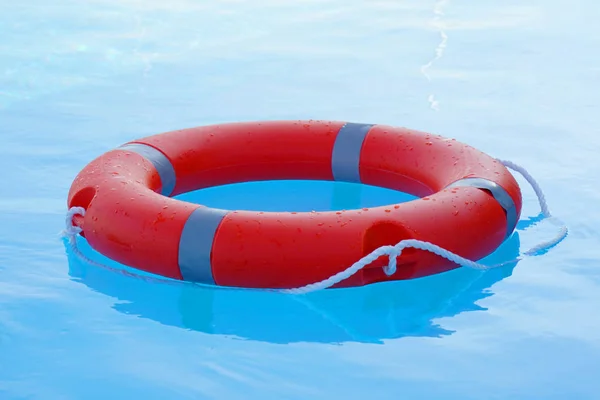 赤いライフブイプールリングは青い水に浮かぶ 生命リング日当たりの良い青い水の上に浮かんでいます プールでの生活リング — ストック写真