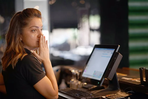 Female bartender made a mistake in the bill, emotion. A barmaid registrating new order by cash-register. A restaurant worker registrating new order by cash-register. The concept of service.