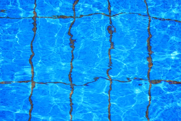 Pure blue water in the pool. Water background. Swimming pool bottom caustics ripple and flow with waves background. Water in swimming pool rippled water detail background.