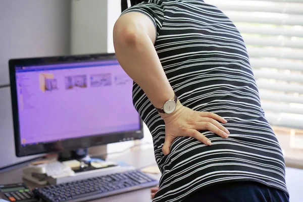 Close-up view of a office worker woman with pain in kidneys. Woman with back ache clasping her hand to her lower back in home. Woman suffering from ribbing pain, waist pain.