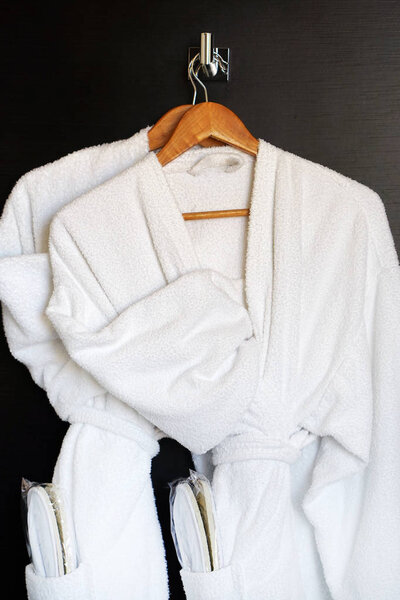 На двери висят два белых халата. Платья на вешалке для дверей
.