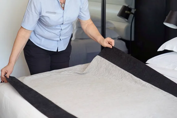 Maid making bed in hotel room. Housekeeper Making Bed