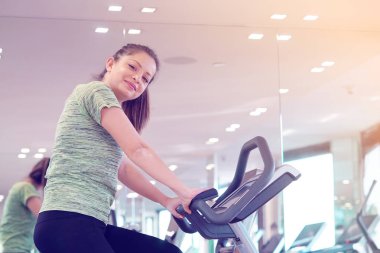 Bir koşu bandı üzerinde çalışan genç kadın fitness spor kulübünde meşgul. Genç kız spor salonunda. Sağlıklı yaşam tarzı, jimnastik, kilo kaybı kavramı. Tonlama.