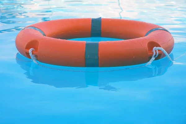赤いライフブイプールリングは青い水に浮かぶ 生命リング日当たりの良い青い水の上に浮かんでいます プールでの生活リング — ストック写真
