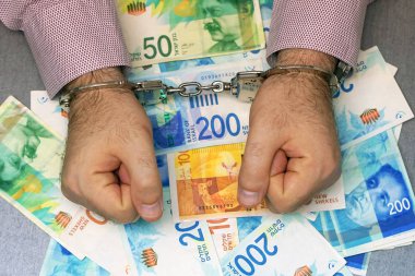Rüşvet İsrail para tutan kelepçeleri ofisinde bir iş adamı. Yakın çekim elleri kelepçeli. Tutuklanan terörist. Mali suç ve yolsuzluk kavramı kirli para. Seçici odak.