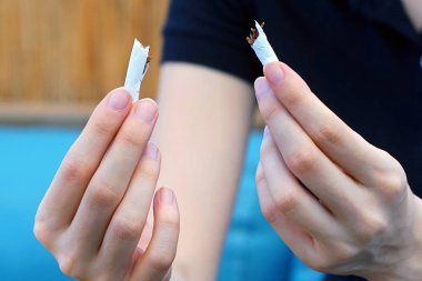 Eller genç kadın sigara yırtılma. Kırık bir sigara onun elinde tutan kız. Sağlıklı bir yaşam tarzı kavramı. Sigarayı.