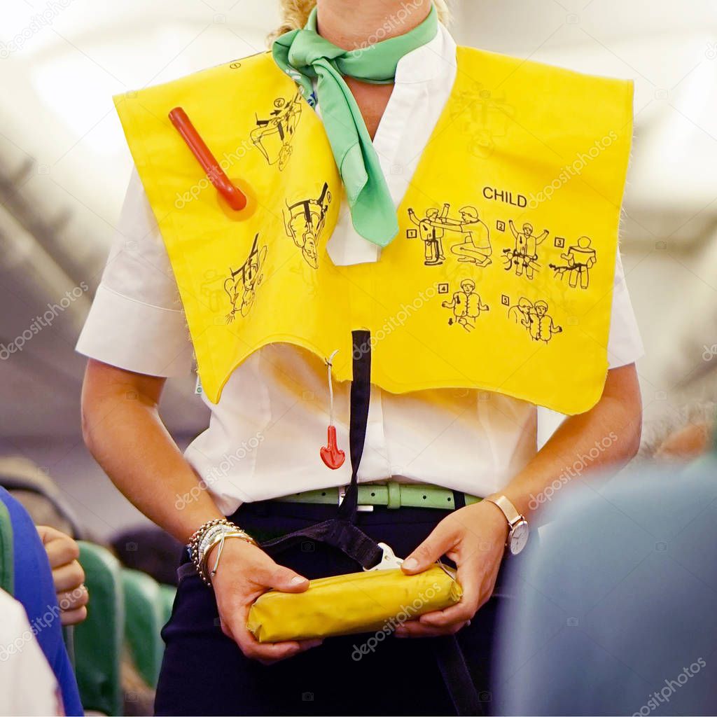 Stewardess in the cabin passenger airplane instructs passengers on safety measures in the event of an emergency
