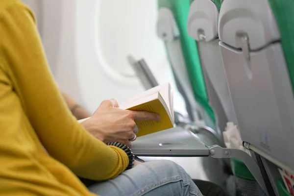 A young man reads a book on the plane with his wife. A man traveling by plane. A man reading a book while flying. The concept of transport