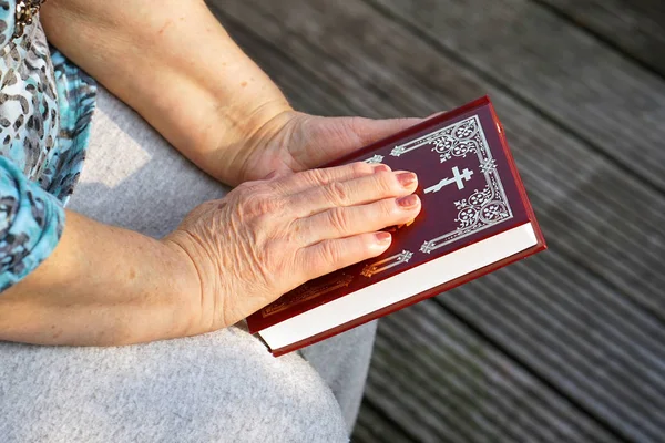 Hand of elderly woman lies on an a Bible, woman praying. Woman hand with Bible praying, Hand in prayer on a Holy Bible in church concept for faith, spirituality and religion