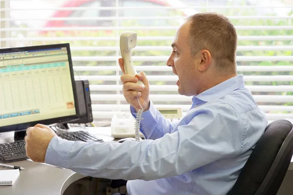 Close-up of an office worker swears with the client by phone. A man is shouting into the phone\'s phone. Funny facial expressions, emotions, reaction of perception, stress, gilding, nerves.